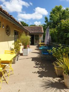 eine Terrasse mit Tischen, einem Sonnenschirm und Pflanzen in der Unterkunft Domaine de Bourgville in Monts-sur-Guesnes
