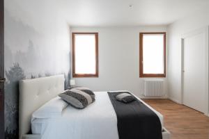 a bedroom with a large white bed with two windows at Apartments in San Marco with Canal View in Venice