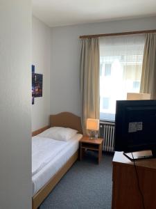 a bedroom with a bed and a tv and a window at Hotel Berg in Cologne