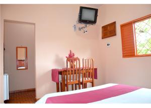 1 dormitorio con cama, mesa y TV en la pared en Agualinda Hotel, en Alter do Chao