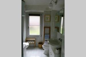 a bathroom with a sink and a toilet and a mirror at Cosy Place in Perledo