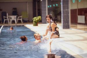 een vrouw en twee kinderen spelen in een zwembad bij Danubius Hotel Annabella in Balatonfüred