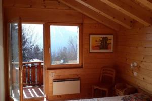 a bedroom in a log cabin with two windows at Chalet La Marendaz in Ovronnaz