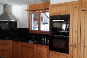 uma cozinha com armários de madeira e um forno de fogão preto em Chalet La Marendaz em Ovronnaz