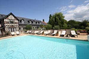 une piscine avec des chaises longues et une maison dans l'établissement Manoir de la Croix-Sonnet, à Trouville-sur-Mer