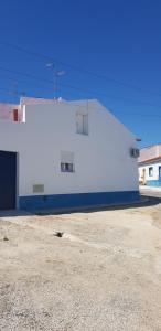 een wit gebouw met een blauwe en witte muur bij Casa o Cantinho in Mourão
