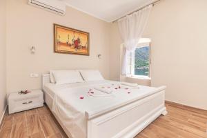 a white bedroom with a white bed with flowers on it at Old Stone Villa Lalosevic in Kotor
