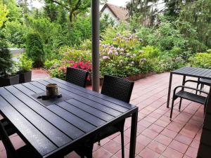 a wooden table and chairs on a patio with flowers at Apartment Frohnau in Berlin