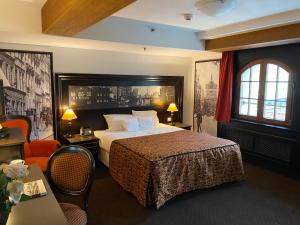 グダニスクにあるホテル グダニスク ブティックのベッド、テーブル、椅子が備わるホテルルームです。