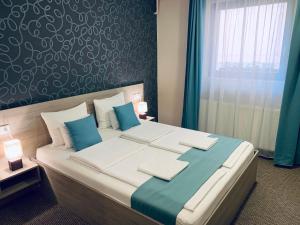 ein Schlafzimmer mit einem großen Bett mit blauen und weißen Kissen in der Unterkunft Thermal Apartman in Makó