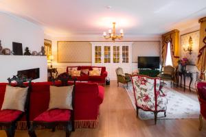 uma sala de estar com sofás vermelhos e cadeiras em Solar Sampaio e Melo em Trancoso