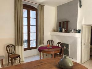 ein Wohnzimmer mit einem Tisch, Stühlen und einem Fenster in der Unterkunft Charmant appartement dans La Catiche de Loutre in Sauve