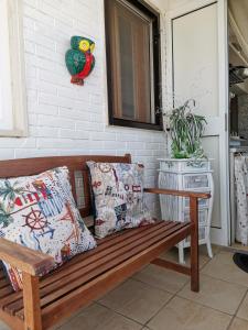 una panca in legno con cuscini su una veranda di Little Paradise casa vacanze a Margherita di Savoia
