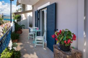 eine Terrasse mit einer blauen Tür und einem Tisch mit roten Blumen in der Unterkunft Kris&Strato's Studio in Lygia