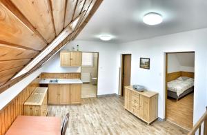 a kitchen with wooden cabinets and a bed in a room at Chaty Ivana 18 a 19 u Hustopecskych jezer in Hustopeče Nad Bečvou