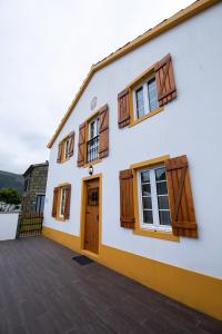 a white building with wooden doors and windows at Sete Cidades Quinta Da Queiró in Sete Cidades