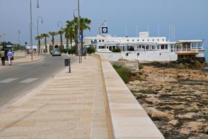 Una acera junto a una calle con palmeras y un edificio. en Le Case del Vento - APPARTAMENTO MAESTRALE, en Torre Canne