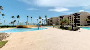 - une piscine avec des palmiers et des bâtiments dans l'établissement Crescent Beach 251, à Humacao