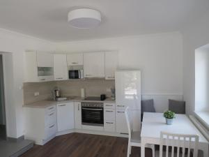 a kitchen with white cabinets and a white table and a table and a white table at Sportpension Strobl in Millstatt