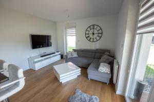 a living room with a couch and a clock on the wall at Apartament nad jeziorem w Iławie- mozliwość wynajęcia motorówki !! in Iława