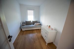 Habitación blanca pequeña con sofá y cómoda en Apartament nad jeziorem w Iławie- mozliwość wynajęcia motorówki !! en Iława