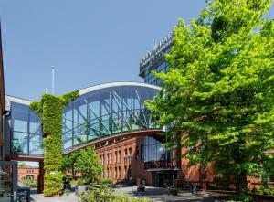 a glass building with a tree in front of it at Super-Apartamenty City Park I BASEN, SAUNA in Poznań