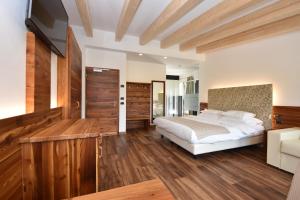 um quarto com uma cama grande e pisos em madeira em Belvedere Dolomites Flower Hotel em Moena