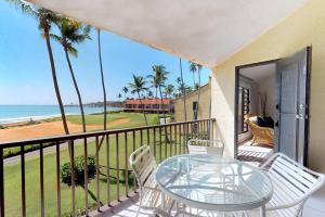 Un balcón con una mesa de cristal y sillas y el océano. en Beach Villa 233, en Humacao