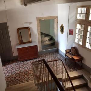 pasillo con espejo, silla y escaleras en Logis Hotel le Prieuré, en Bourg-Saint-Andéol