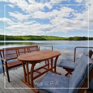 una mesa de madera y sillas en la cubierta de un barco en wySPA Kaszuby-domki na wodzie, en Ostrzyce