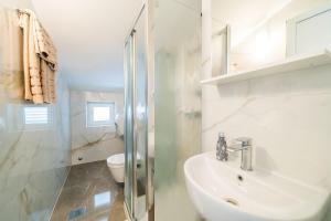 biała łazienka z umywalką i toaletą w obiekcie Rooms & Apartments Barišić w mieście Mlini