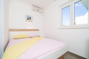 Cama en habitación blanca con ventana en Rooms & Apartments Barišić, en Mlini