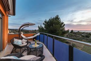 una donna seduta su una sedia su un balcone con ombrellone di Villa Veronica with great sea view & private pool - calm & relax holidays in Istria a Peroj