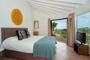 a bedroom with a bed and a tv and a balcony at Caballito de Mar Boutique Hotel in Moraira