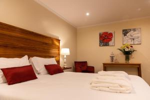 a bedroom with a bed with white sheets and red pillows at Sete Cidades Quinta Da Queiró in Sete Cidades