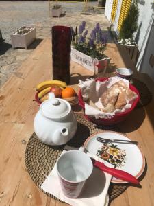 uma mesa com um bule de chá e uma taça de fruta em Casinha dos Relógios em Penhas da Saúde