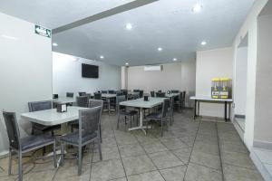 a dining room with tables and chairs and a tv at Hotel Plaza del Arco - Monterrey in Monterrey