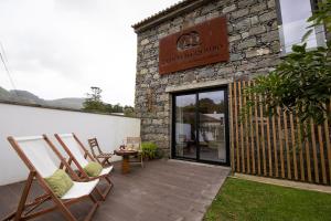 a patio with chairs and a sign on a building at Sete Cidades Quinta Da Queiró in Sete Cidades
