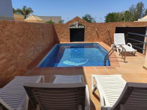 a swimming pool on a patio with chairs and a table at Casa das Figuras in Faro