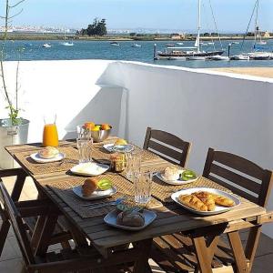 a wooden table with food on it with a view of the water at Casa do Rio - Riverside House in Seixal