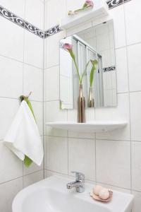 een badkamer met een wastafel en een spiegel en een vaas met bloemen bij Hotel Arche in Berlijn