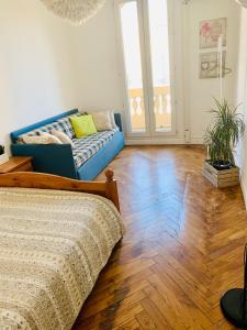 a bedroom with a blue couch and a wooden floor at Appartment Le Charme du Bourgeois in Nice