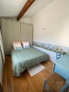 Un pequeño dormitorio con una cama verde y una silla en Au Mas Retz De Jade, en Chauvé