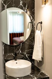 a bathroom with a white sink and a mirror at Living in Nafplio Luxury Apartments in Nafplio