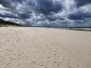 une plage de sable avec un ciel nuageux et l'océan dans l'établissement Jantar 4 Park Bursztynowa, à Jantar