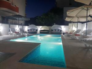 a swimming pool with chairs and umbrellas on a building at Villa Medusa Apartments in Dobra Voda