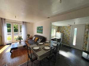 a living room with a table and chairs and a kitchen at Santa Maria in Saint-Ouen-de-Mimbré