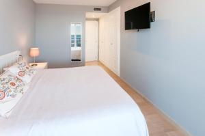 a bedroom with a white bed and a flat screen tv at AG Turquesa Premium in Gandía