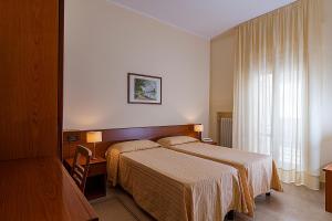 a hotel room with two beds and a window at Il Nocchiero City Hotel in Soverato Marina