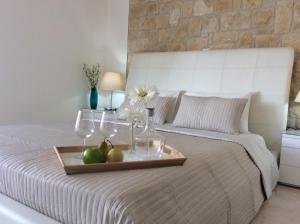 a tray with fruit and wine glasses on a bed at Dream House Latchi Villa in Polis Chrysochous